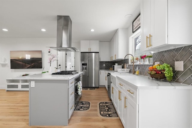 kitchen with a kitchen island, white cabinets, appliances with stainless steel finishes, light wood-type flooring, and island range hood