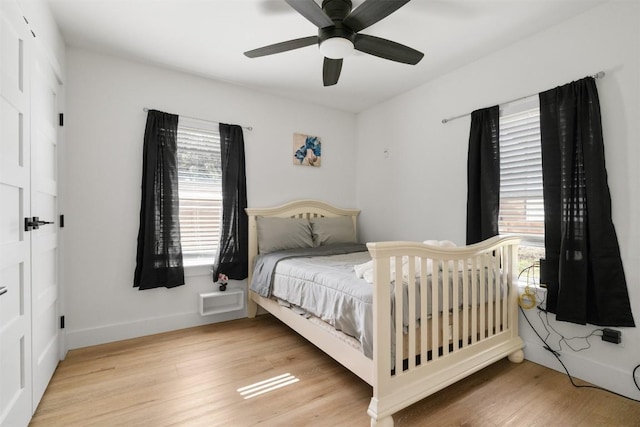 bedroom with multiple windows, ceiling fan, and wood finished floors