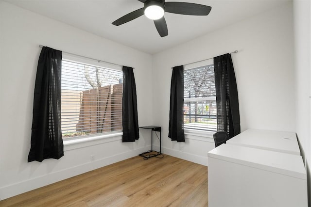 interior space with light wood finished floors, ceiling fan, baseboards, and washing machine and clothes dryer