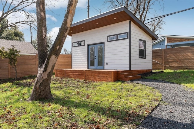 rear view of house featuring french doors, an outbuilding, and fence