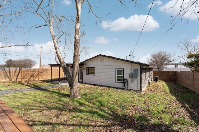 rear view of property featuring central AC unit, a lawn, board and batten siding, and a fenced backyard