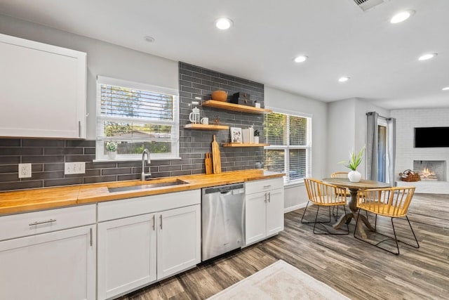 kitchen with butcher block counters, dishwasher, decorative backsplash, wood finished floors, and a sink