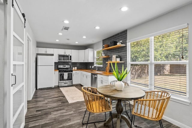 kitchen with white cabinets, butcher block counters, stainless steel appliances, and dark wood-style flooring