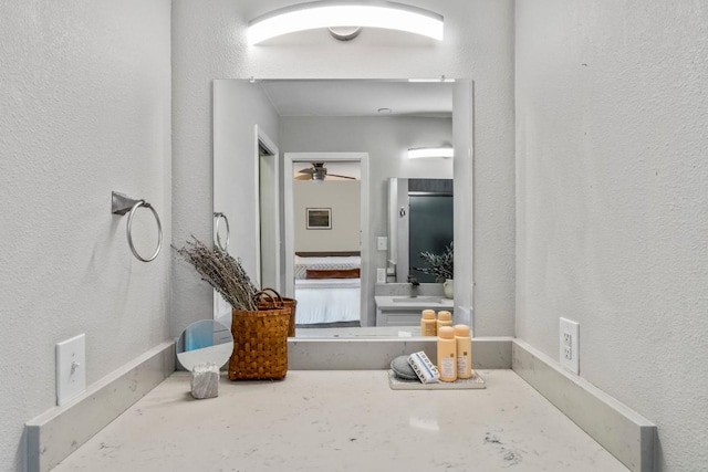 bathroom with ceiling fan, vanity, and a textured wall