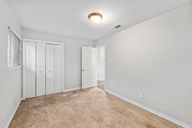 unfurnished bedroom with a closet, baseboards, visible vents, and carpet flooring