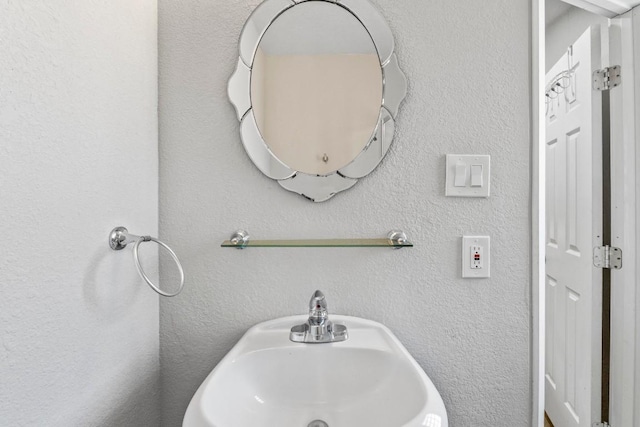 bathroom featuring a textured wall and a sink