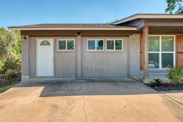 view of exterior entry featuring brick siding and concrete driveway