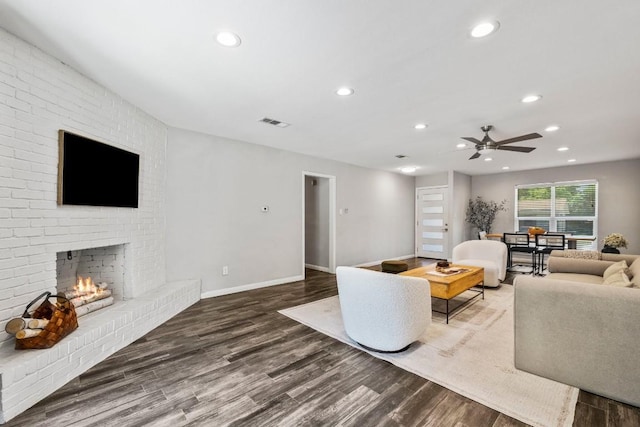 living area featuring visible vents, wood finished floors, recessed lighting, baseboards, and a brick fireplace