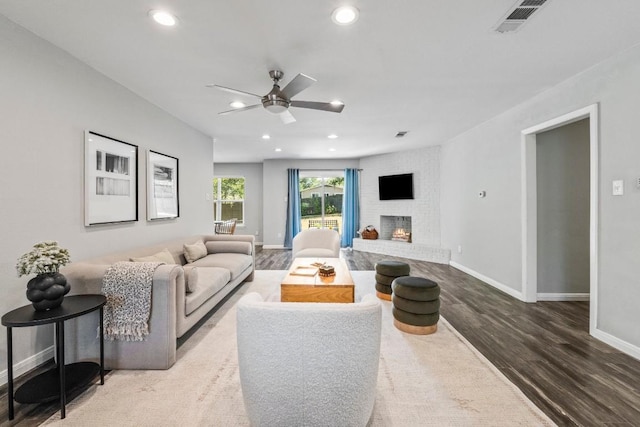 living area featuring visible vents, a fireplace, baseboards, and wood finished floors