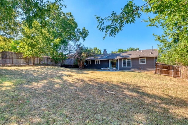 back of property with a lawn, a fenced backyard, and a chimney