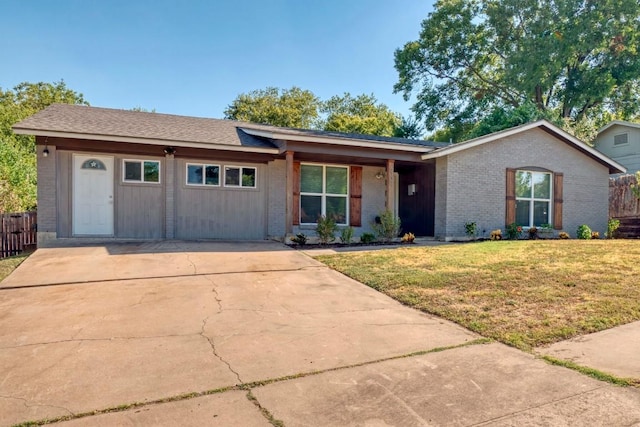 ranch-style home with a front yard, fence, brick siding, and driveway