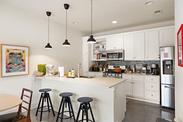 kitchen featuring visible vents, a breakfast bar, a sink, appliances with stainless steel finishes, and decorative backsplash