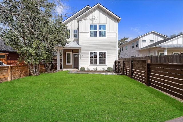 rear view of house with a lawn, board and batten siding, and a fenced backyard