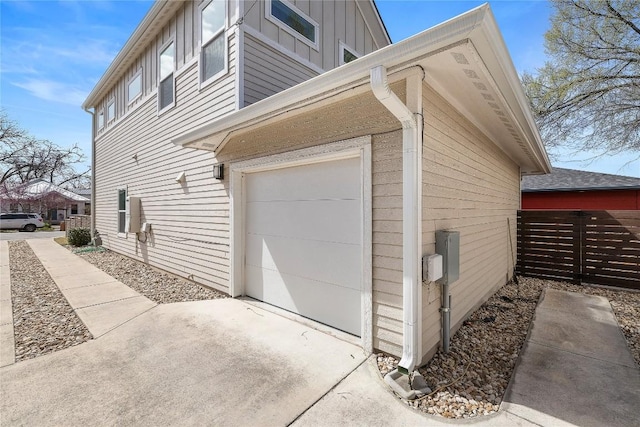 view of home's exterior featuring a garage, board and batten siding, concrete driveway, and fence