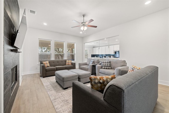 living room with visible vents, recessed lighting, light wood-style floors, baseboards, and a tile fireplace