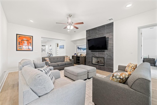 living room featuring visible vents, light wood-style flooring, recessed lighting, ceiling fan, and a tile fireplace