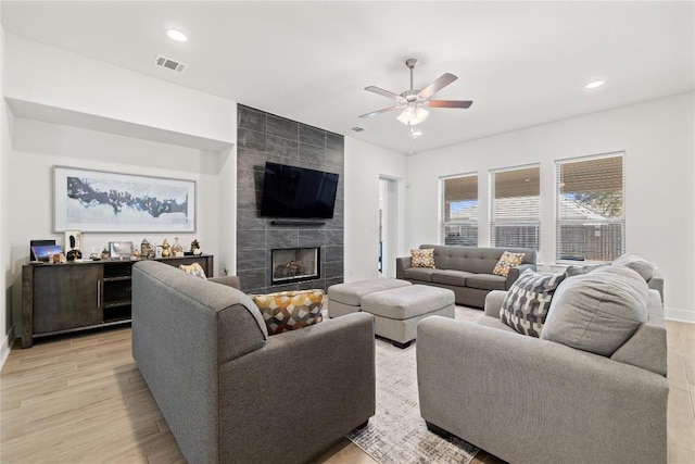 living room with recessed lighting, visible vents, a tile fireplace, and light wood finished floors