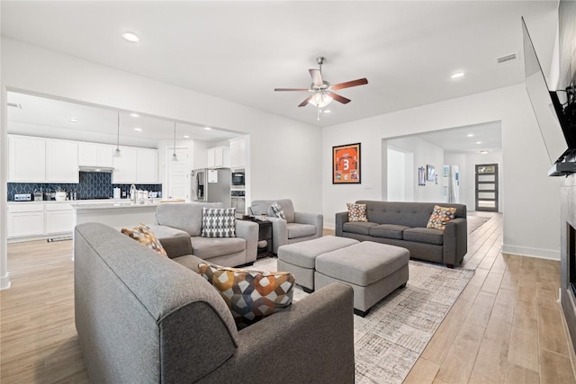 living area featuring visible vents, recessed lighting, a fireplace, light wood-style floors, and a ceiling fan