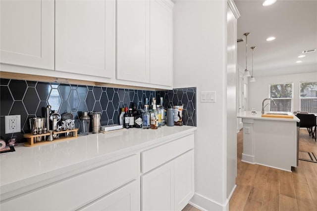 bar featuring visible vents, light wood finished floors, recessed lighting, a sink, and backsplash