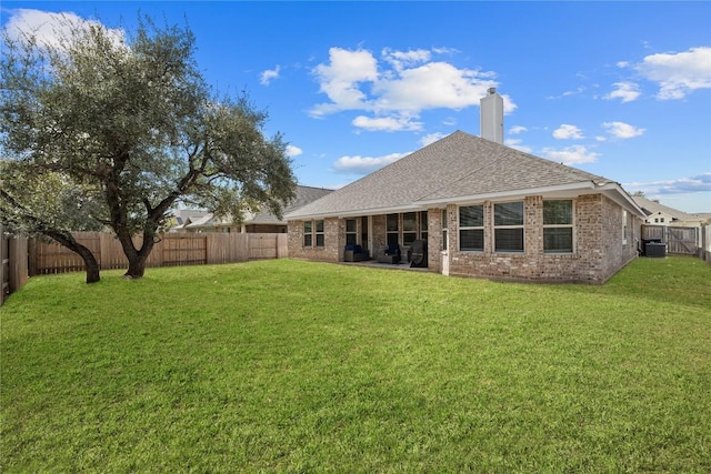 back of house with roof with shingles, a fenced backyard, a chimney, a lawn, and brick siding