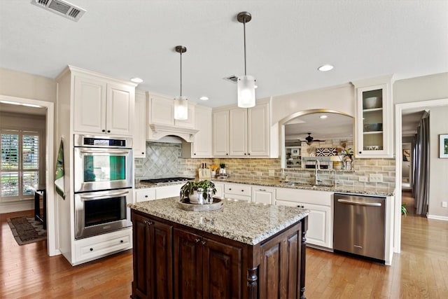 kitchen featuring visible vents, light wood-type flooring, appliances with stainless steel finishes, white cabinets, and a sink