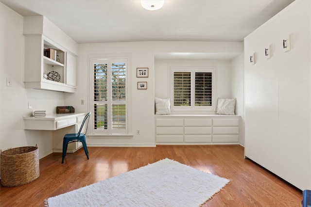 office area featuring wood finished floors, built in desk, and baseboards