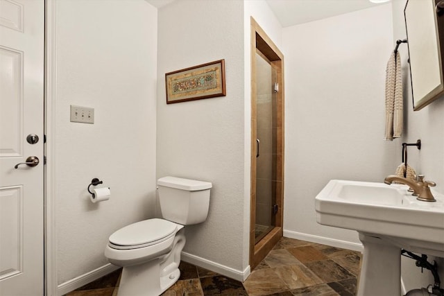 full bathroom with a tile shower, toilet, stone finish flooring, and baseboards