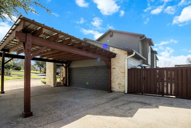 view of home's exterior with stone siding, an attached garage, and fence