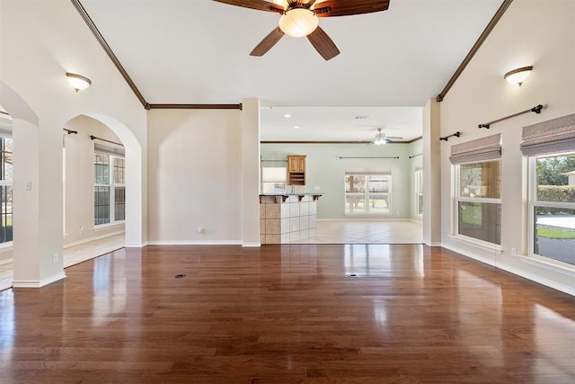 194 Brushy Creek Trl, Hutto, TX 78634 - unfurnished living room featuring a ceiling fan, wood finished floors, crown molding, arched walkways, and baseboards
