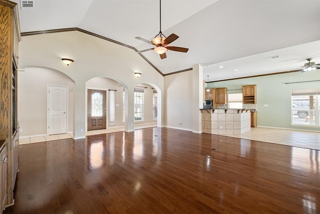 194 Brushy Creek Trl, Hutto, TX 78634 - unfurnished living room with ceiling fan, arched walkways, vaulted ceiling, healthy amount of natural light, and light wood-type flooring