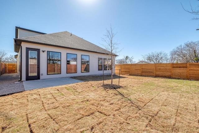 rear view of property featuring a yard, stucco siding, a patio, and a fenced backyard