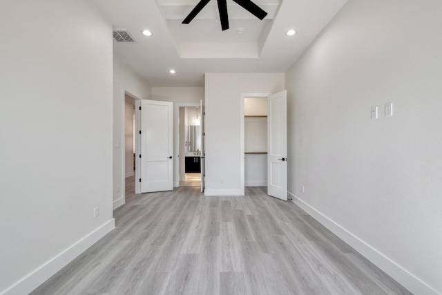 unfurnished bedroom featuring baseboards, visible vents, a tray ceiling, recessed lighting, and light wood-type flooring