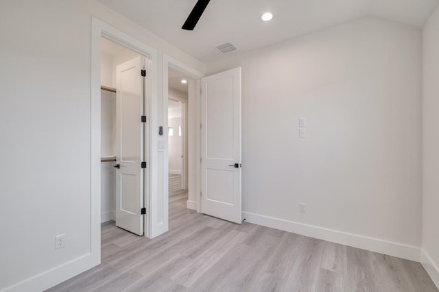 unfurnished bedroom featuring visible vents, baseboards, a walk in closet, and light wood finished floors