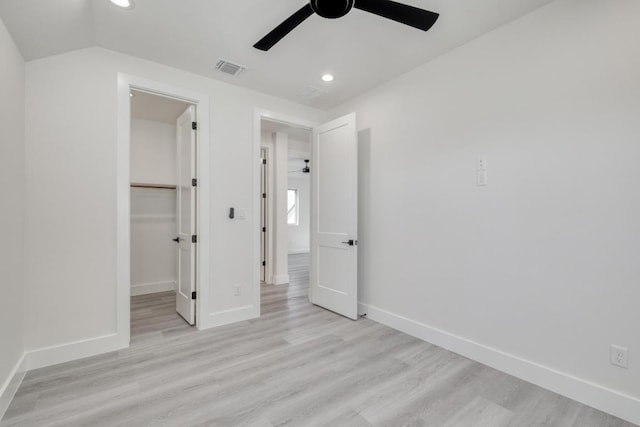 unfurnished bedroom with a walk in closet, light wood-style floors, and baseboards