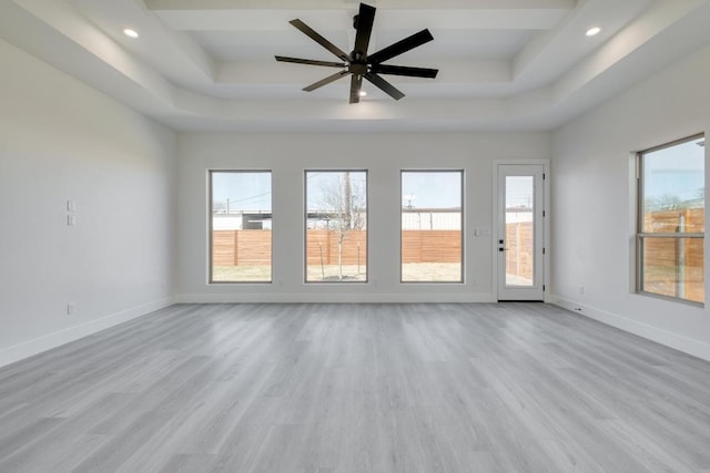 spare room featuring a tray ceiling, recessed lighting, wood finished floors, and baseboards