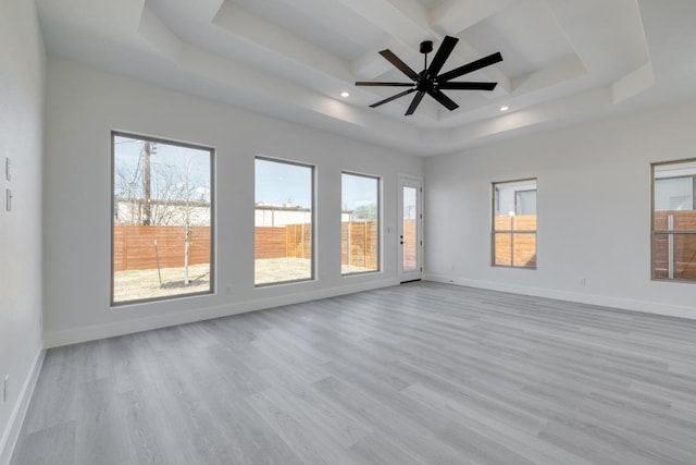 spare room featuring baseboards, a raised ceiling, and wood finished floors