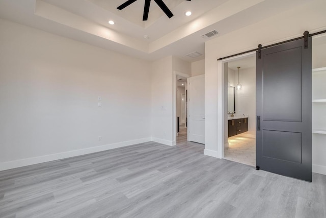 unfurnished bedroom featuring visible vents, baseboards, recessed lighting, light wood-style floors, and a barn door