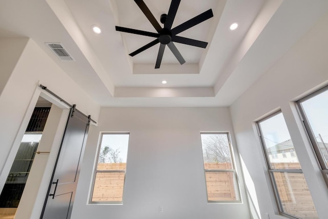 interior space with visible vents, a ceiling fan, recessed lighting, a barn door, and a raised ceiling