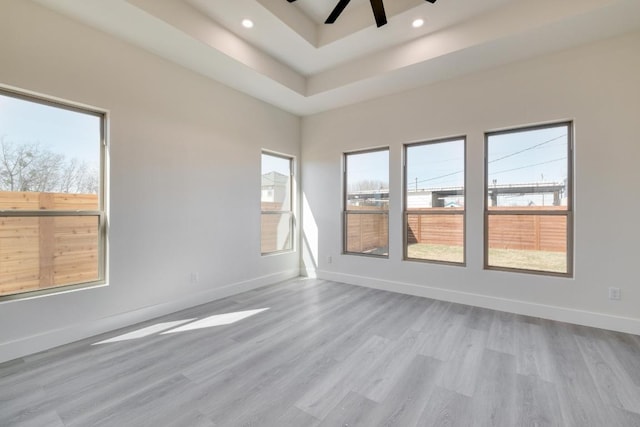 unfurnished room featuring baseboards, recessed lighting, ceiling fan, light wood-style floors, and a raised ceiling