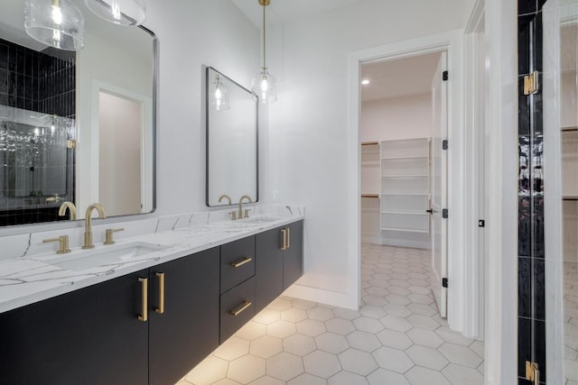 bathroom with a sink, double vanity, a spacious closet, and a walk in shower