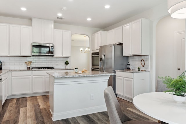1429 Freer Cv, Leander, TX 78641 - kitchen with stainless steel appliances, arched walkways, backsplash, white cabinets, and dark wood finished floors