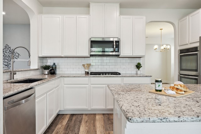 1429 Freer Cv, Leander, TX 78641 - kitchen with stainless steel appliances, arched walkways, white cabinetry, and dark wood-style flooring