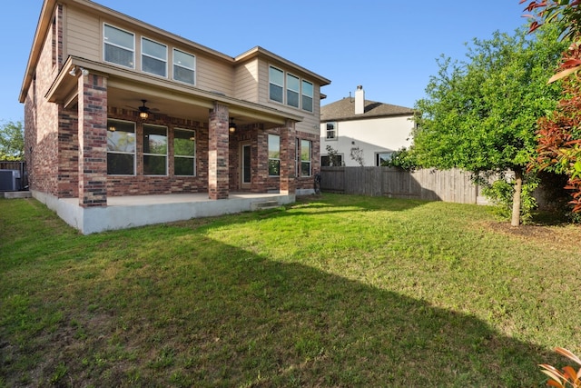 rear view of house with brick siding, ceiling fan, a lawn, a fenced backyard, and a patio area