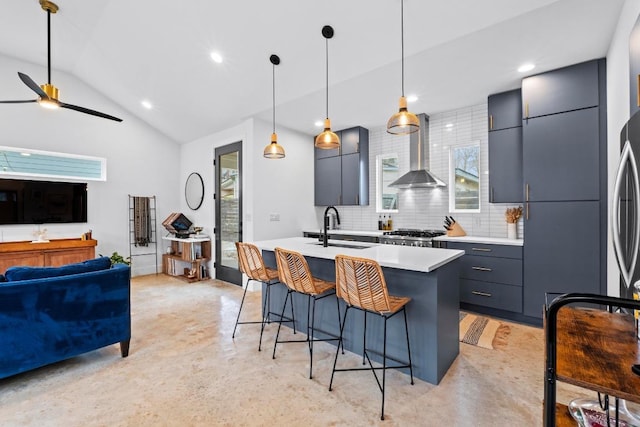 kitchen with wall chimney range hood, a sink, light countertops, a kitchen breakfast bar, and modern cabinets