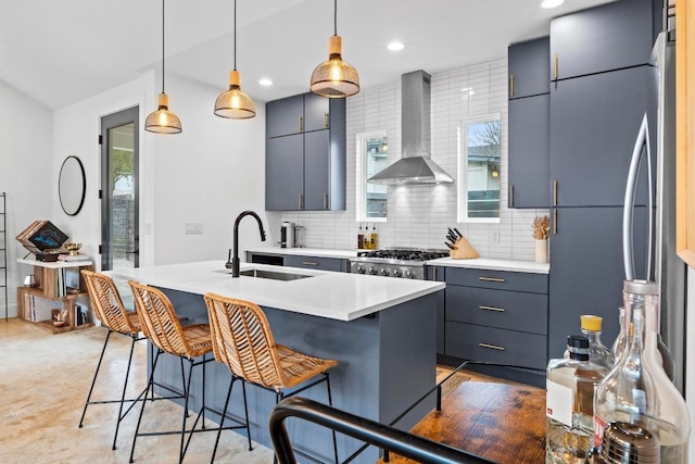 kitchen with tasteful backsplash, a breakfast bar, stainless steel refrigerator, wall chimney exhaust hood, and a sink