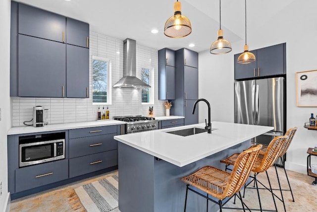 kitchen featuring a breakfast bar, decorative backsplash, stainless steel appliances, wall chimney exhaust hood, and a sink