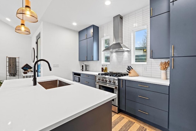 kitchen featuring a sink, stainless steel stove, light countertops, wall chimney exhaust hood, and tasteful backsplash