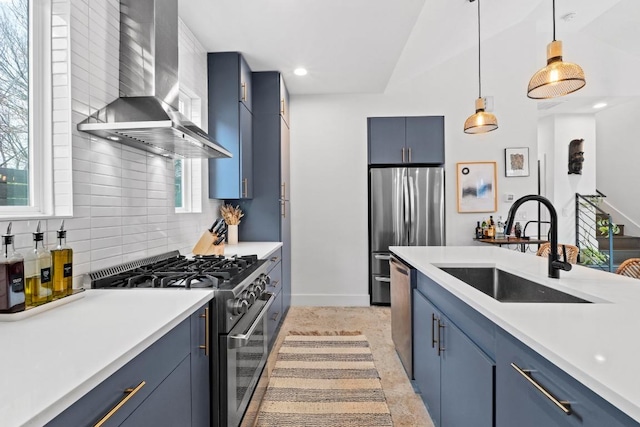 kitchen with backsplash, blue cabinets, stainless steel appliances, wall chimney exhaust hood, and a sink