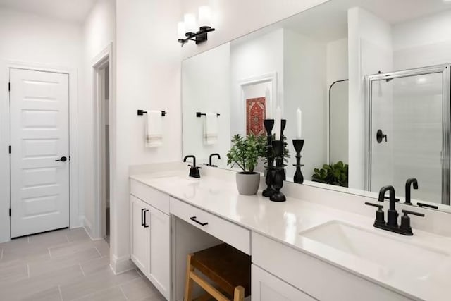 bathroom featuring double vanity, a stall shower, and a sink