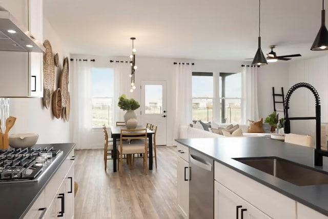 kitchen featuring a sink, dark countertops, white cabinetry, stainless steel appliances, and exhaust hood